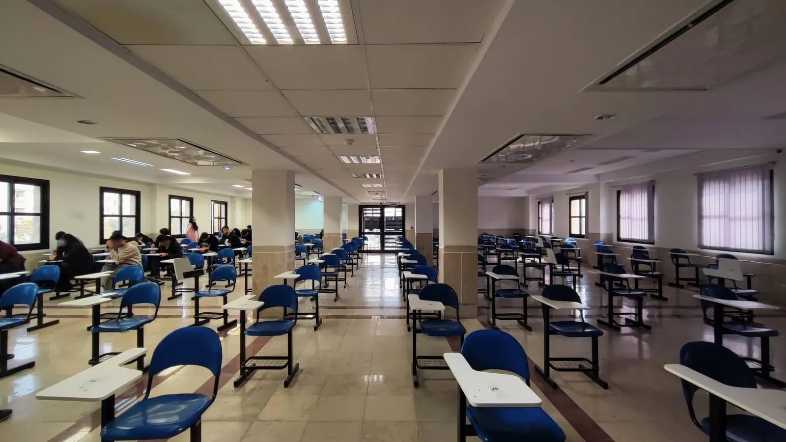 Spaced individual desks laid out in an examination hall