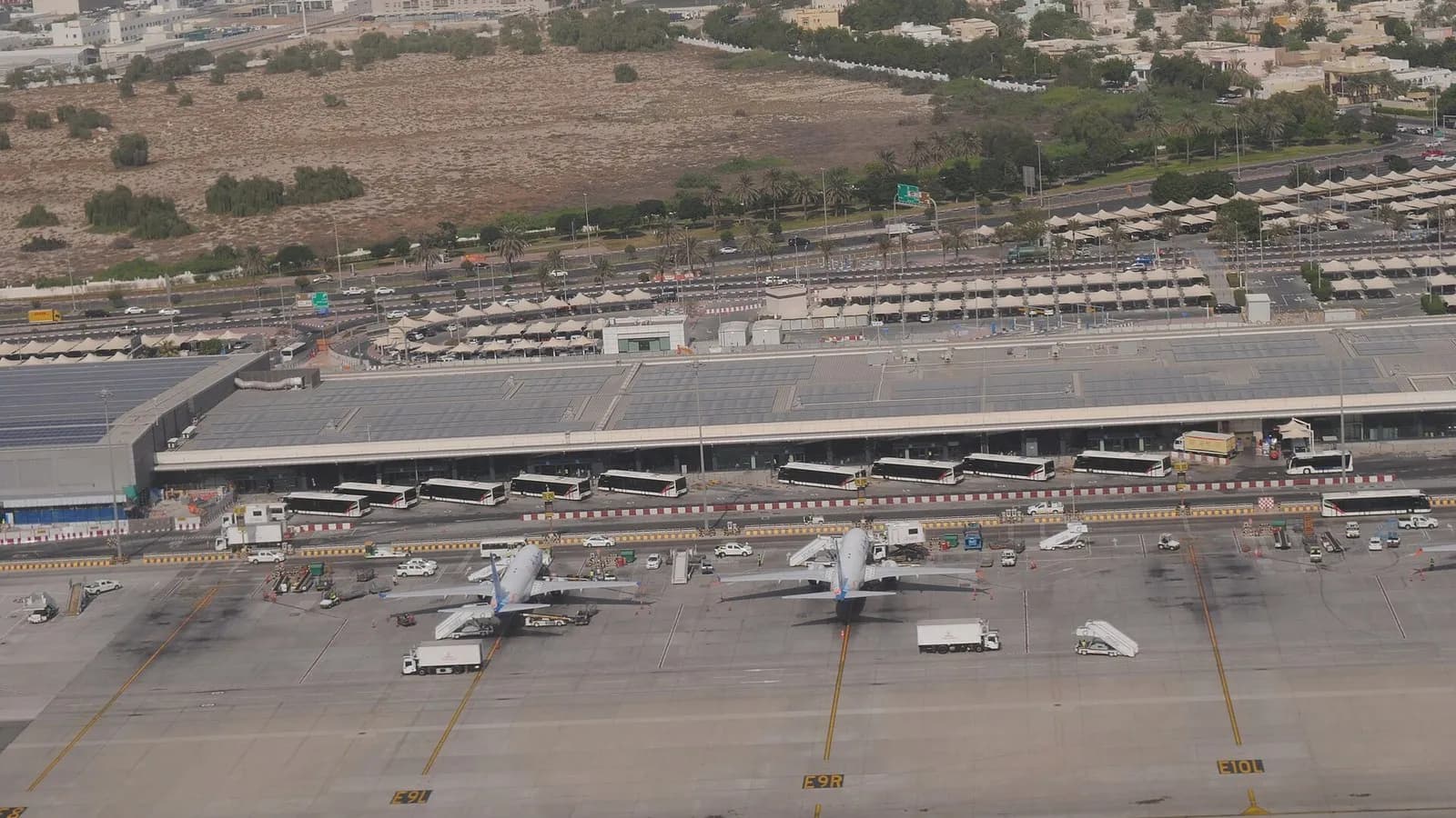 Aircraft parked at stands on the Terminal 2 apron at Dubai International Airport with the long terminal building and desert scrub behind, photographed on 24 October 2024, a file photograph of the airport and not of this winter's schedules