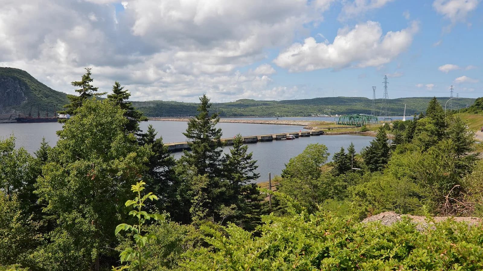 The Strait of Canso at Port Hastings in Nova Scotia, with a causeway and green hills under a blue sky, photographed on 26 July 2022, a file photograph of the strait and not of the planned data centre site
