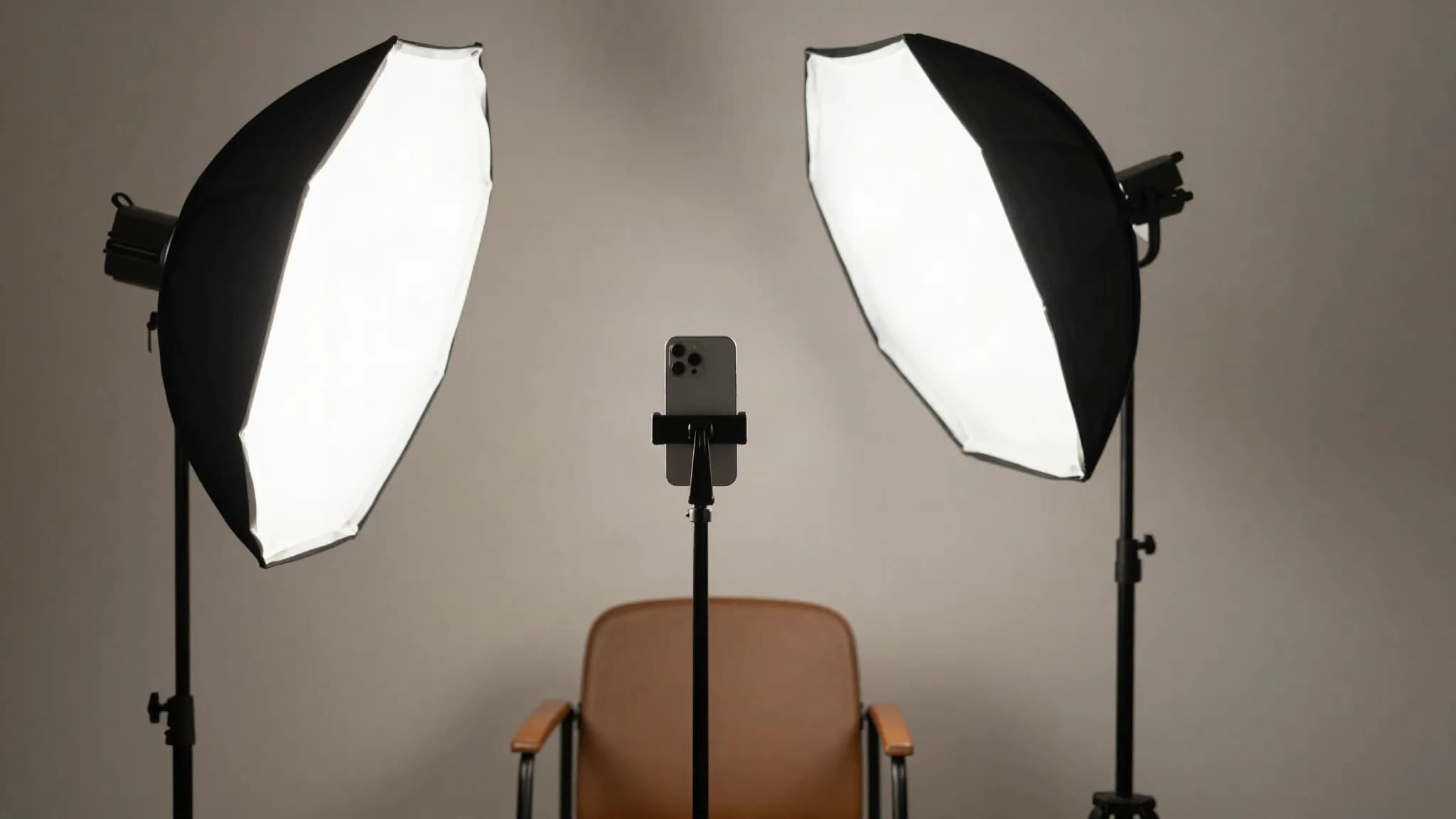A phone on a tripod and softbox facing an empty chair