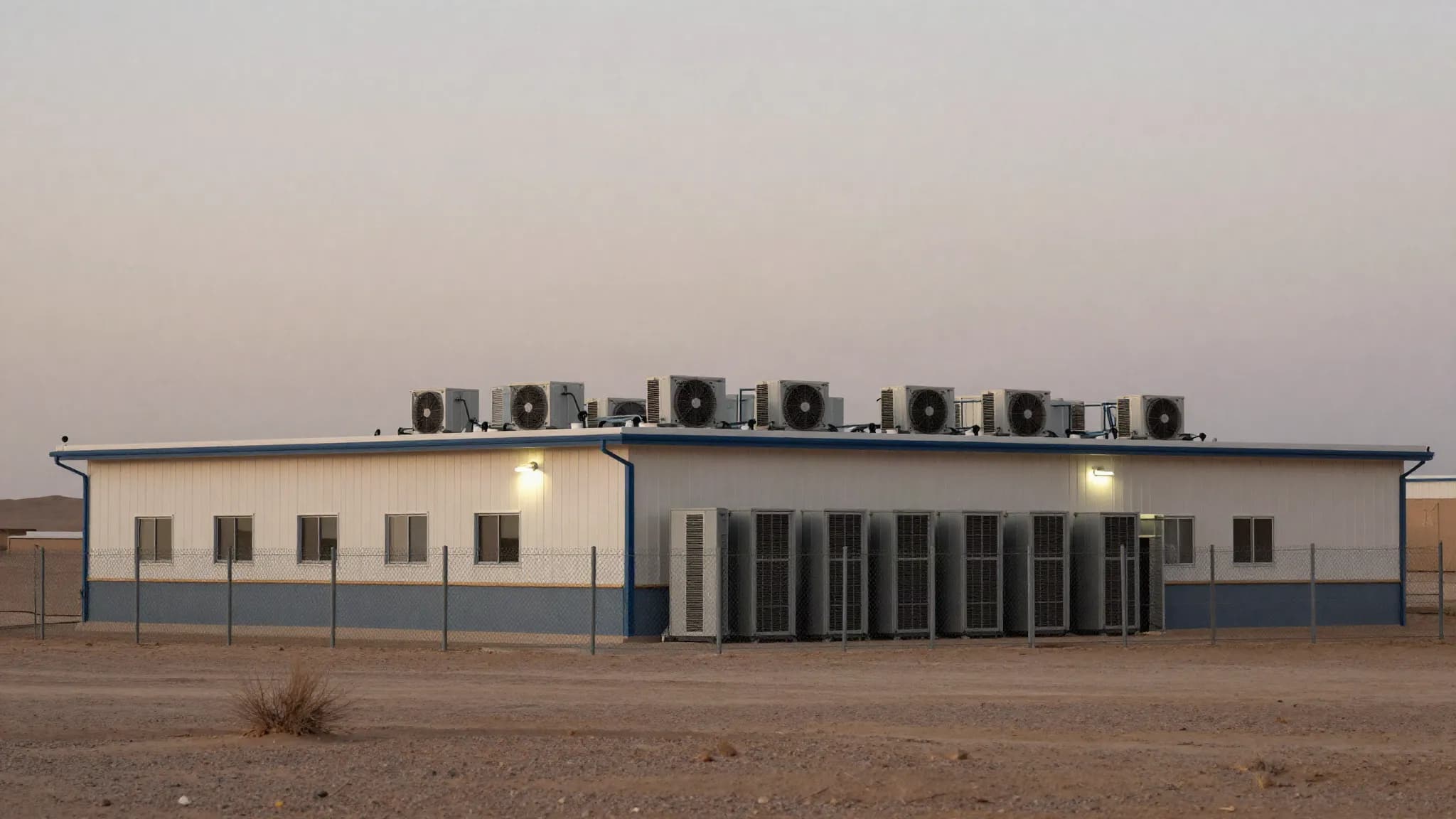 A data centre behind a perimeter fence in the desert at dusk