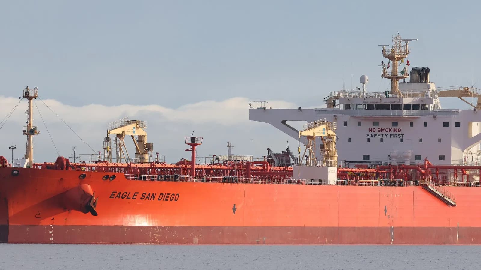 A loaded crude oil tanker alongside, its red hull low in the water and the accommodation block and bridge visible aft