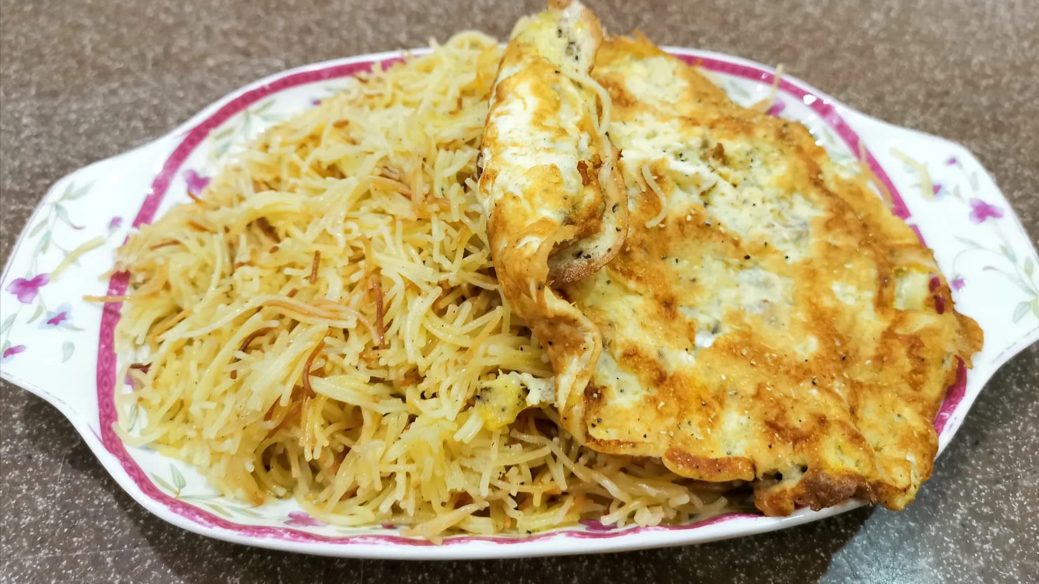 Golden saffron vermicelli on a plate topped with a pale flat omelette