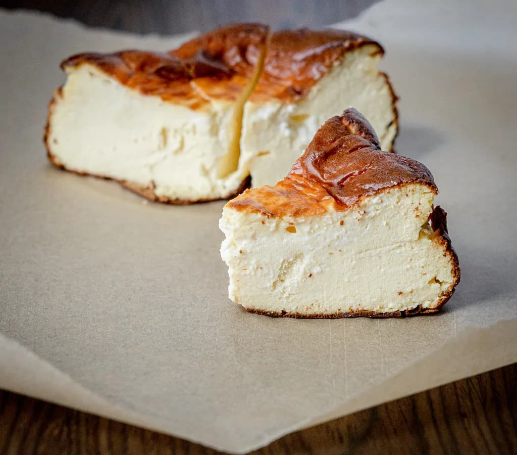 A wedge of Basque burnt cheesecake with a deeply caramelized dark top and a soft, pale, wobbling custard center