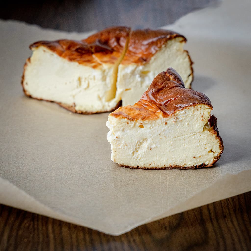 A wedge of Basque burnt cheesecake with a deeply caramelized dark top and a soft, pale, wobbling custard center