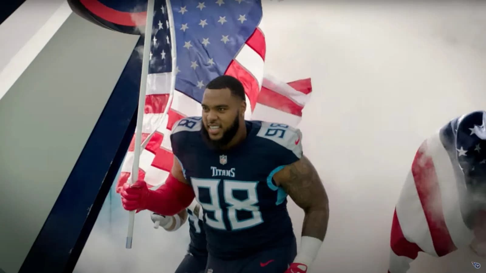 Tennessee Titans defensive tackle Jeffery Simmons, number 98 in a navy jersey, running onto the field at Nissan Stadium through smoke carrying an American flag before a game against the New York Giants on 11 September 2022, a file image of Simmons with his former team and not of the trade or of him in a Bears uniform