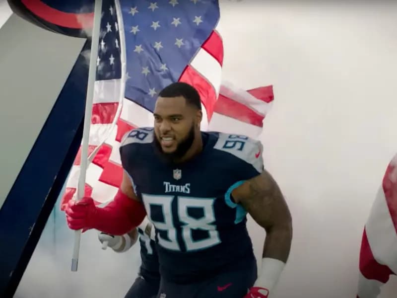 Tennessee Titans defensive tackle Jeffery Simmons, number 98 in a navy jersey, running onto the field at Nissan Stadium through smoke carrying an American flag before a game against the New York Giants on 11 September 2022, a file image of Simmons with his former team and not of the trade or of him in a Bears uniform