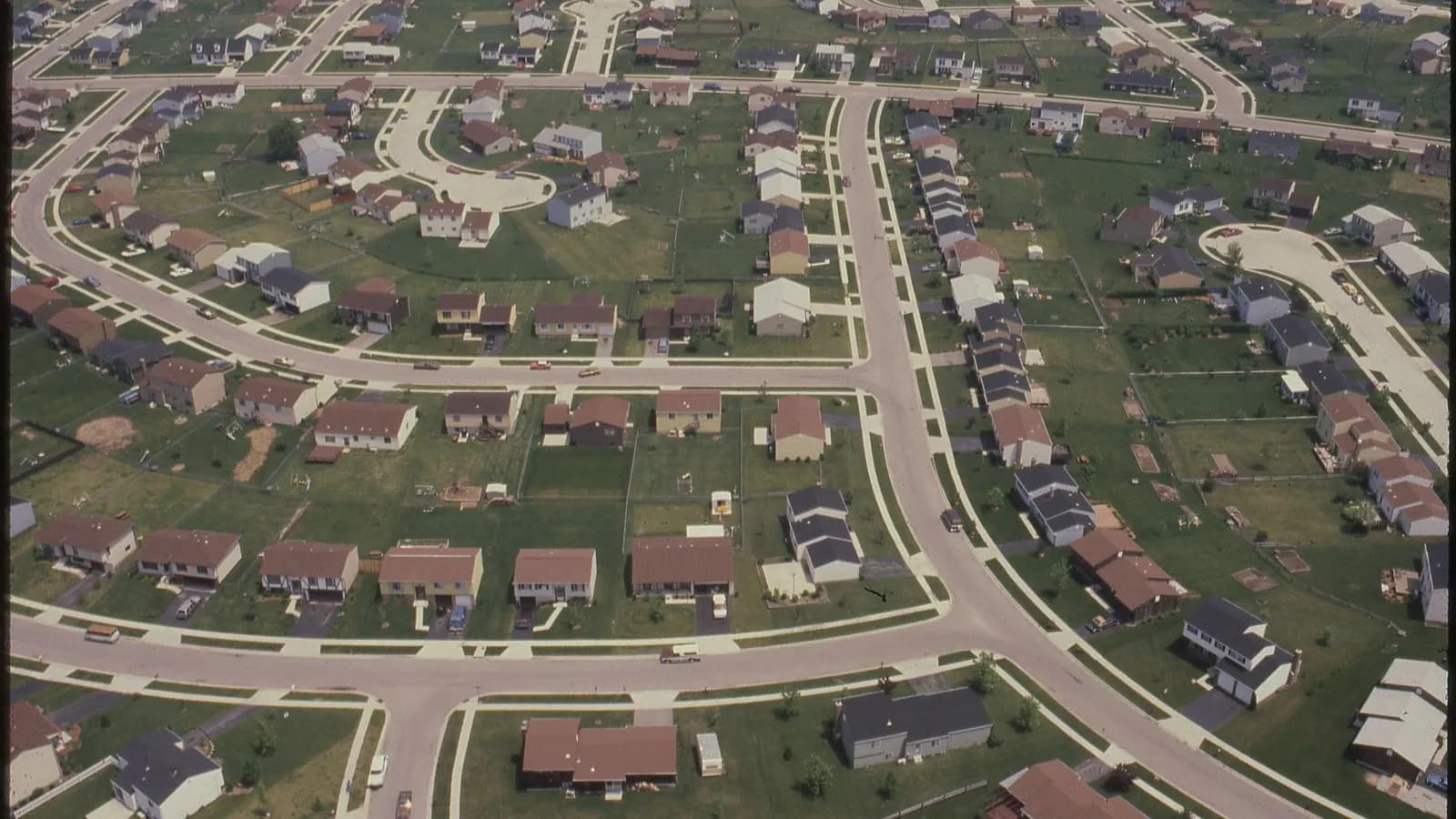 An aerial view of an American residential subdivision of detached houses on curving streets