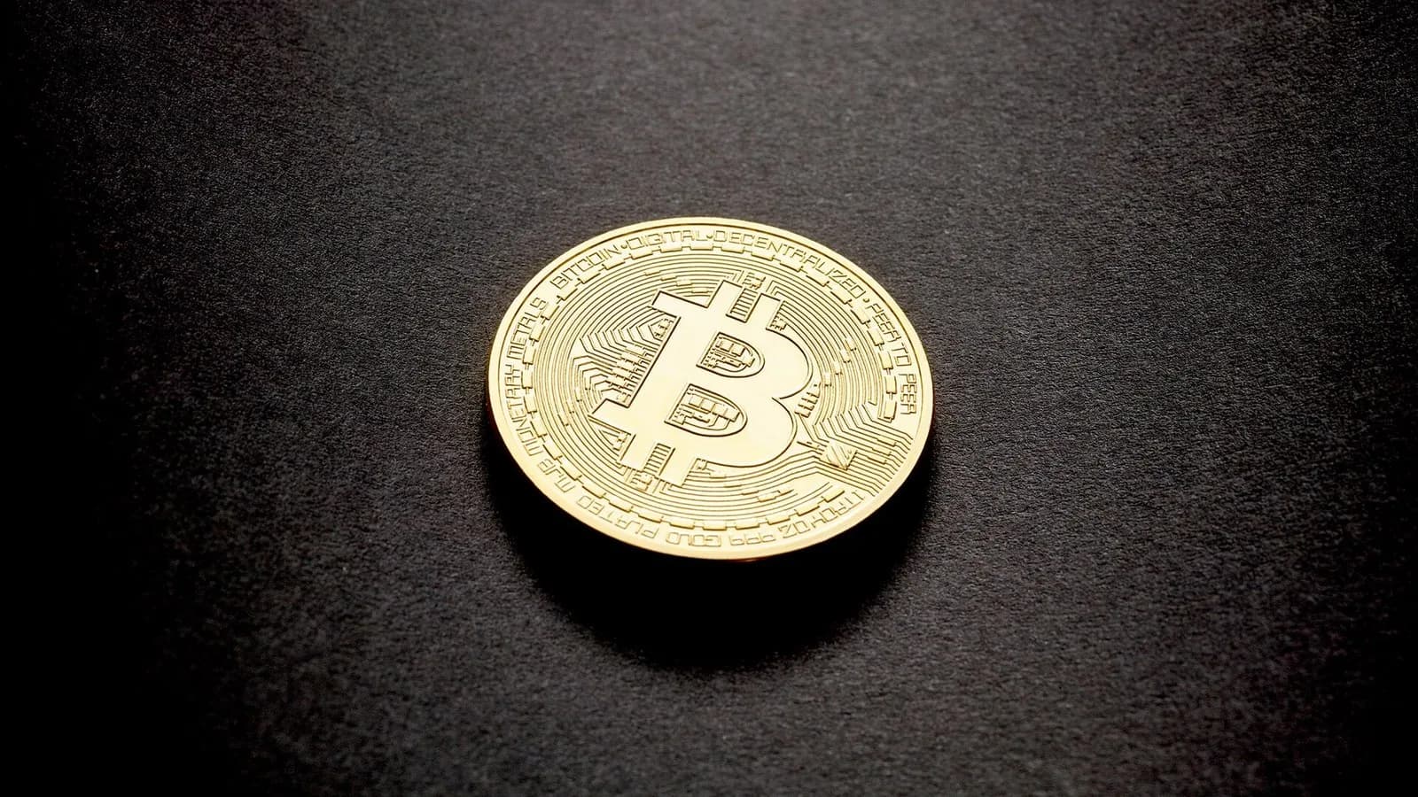 A single gold-coloured physical bitcoin coin lying on a dark surface, photographed on 14 February 2018, a stock illustration of bitcoin and not of Thursday's price move