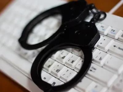 A pair of black handcuffs lying on a white computer keyboard, an undated file photograph illustrative of cybercrime and not of the MONST3R-AI tool or its sellers