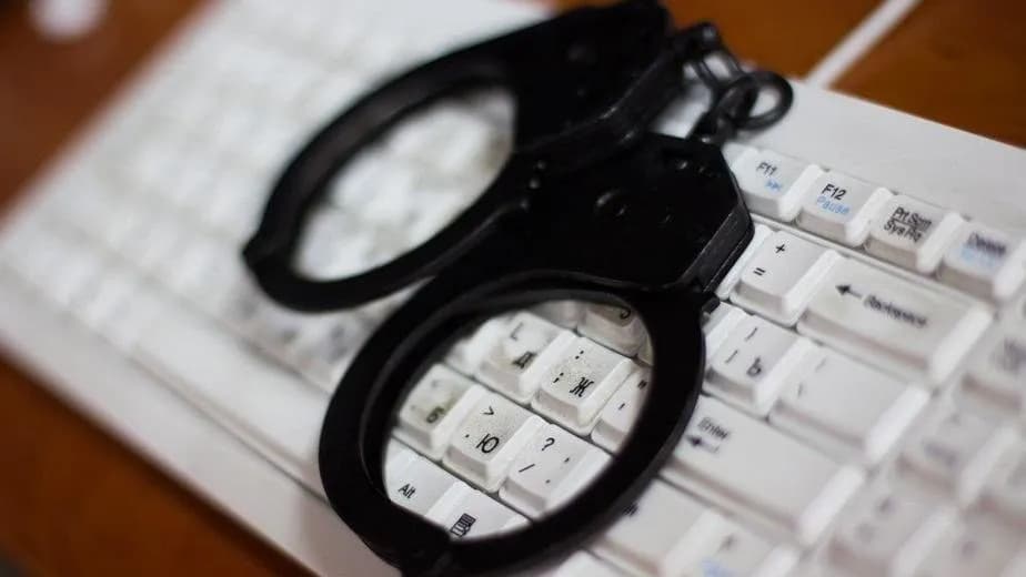 A pair of black handcuffs lying on a white computer keyboard, an undated file photograph illustrative of cybercrime and not of the MONST3R-AI tool or its sellers