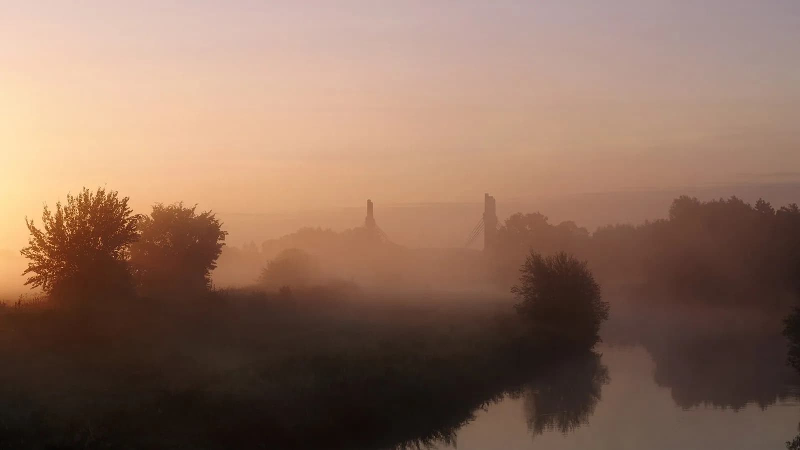 Mist over a river at first light, the sun still low enough to be diffused by the fog