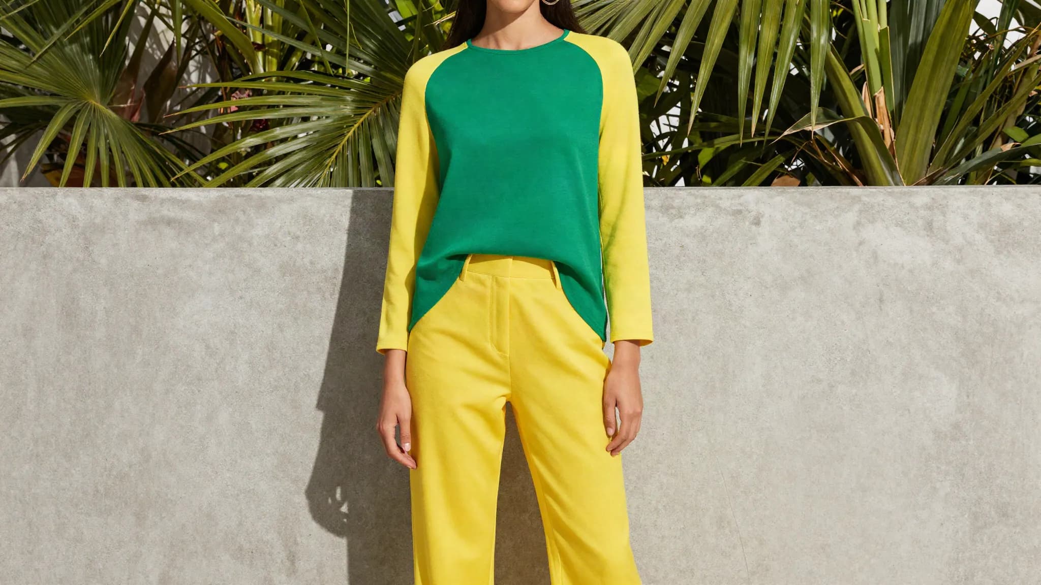 A vivid yellow and green outfit against a sunlit wall