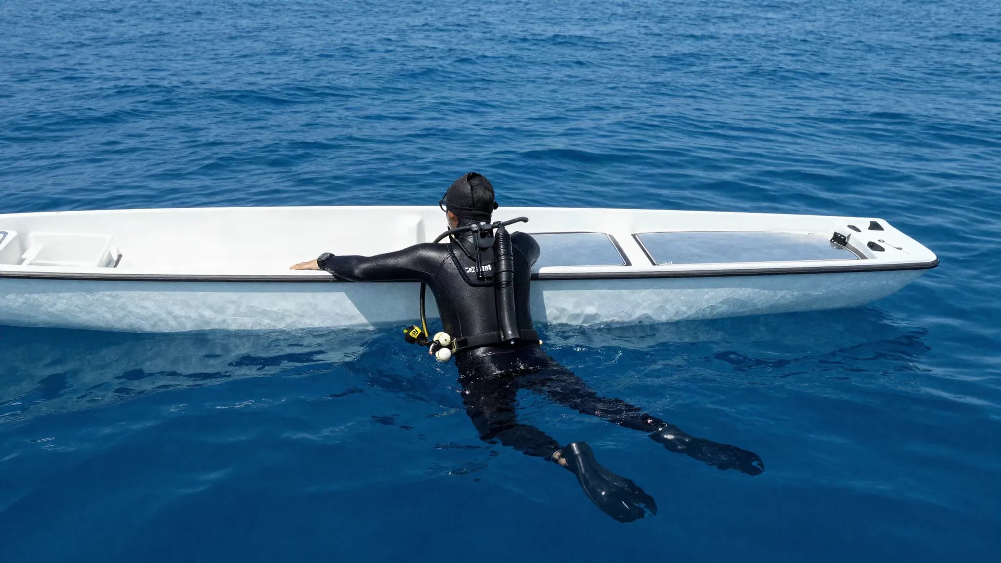 A freediver resting at the surface beside a dive boat