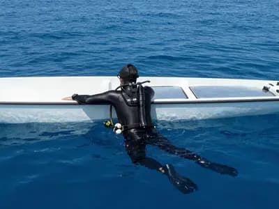 A freediver resting at the surface beside a dive boat