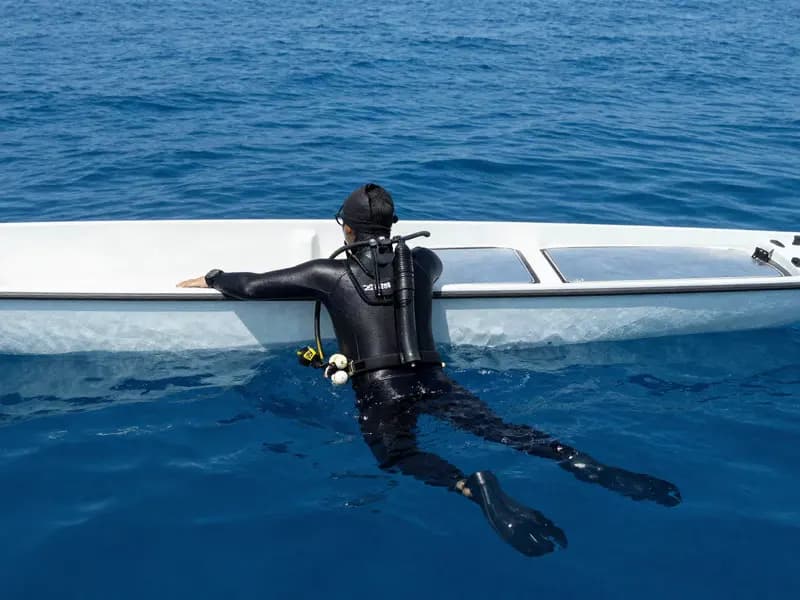 A freediver resting at the surface beside a dive boat