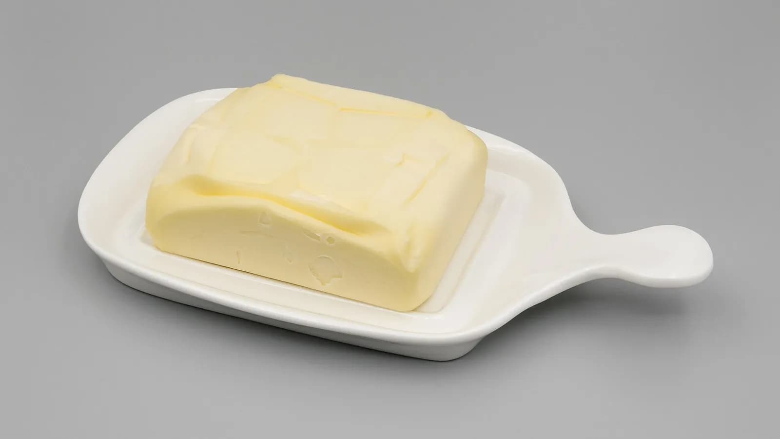 A rectangular block of pale yellow butter on a white dish against a grey background, photographed on 14 May 2023, a file photograph illustrative of foods high in saturated fat and not of the trial's diets