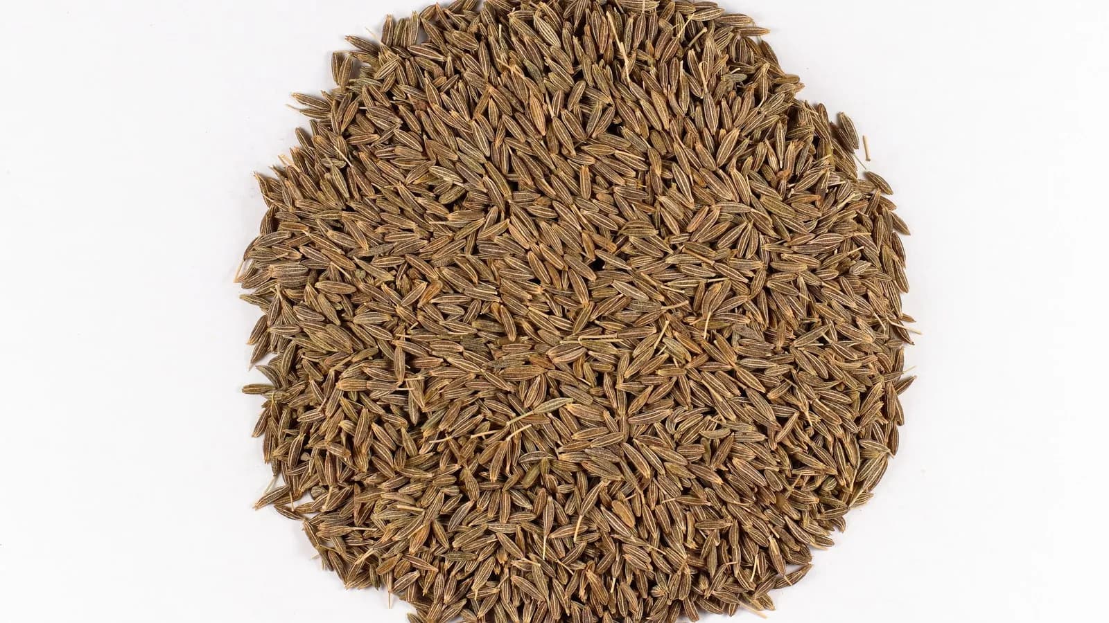 Whole cumin seeds photographed close up against white. Cumin is the first of the three seeds in this infusion and the one that dominates if you use too much