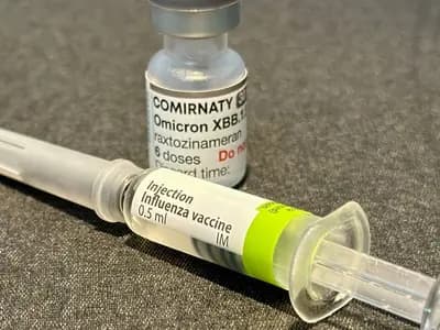 A COVID-19 vaccine vial alongside an influenza vaccine vial, illustrative of the kind of shots caught up in the CDC's stalled guidance process and not the specific mRNA flu vaccine named in this report, photographed in October 2023