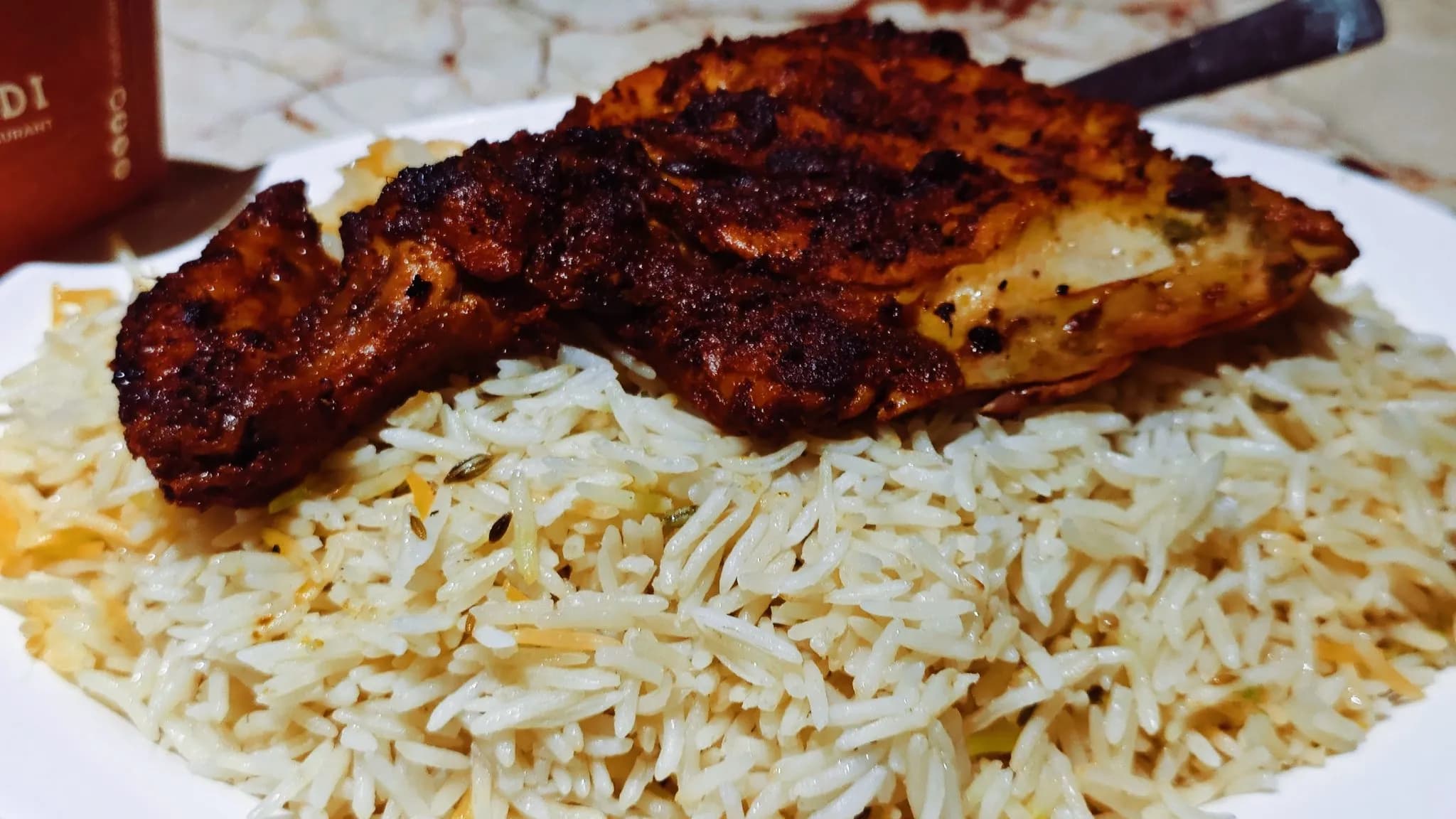 Platter of chicken machboos with golden basmati rice, tender chicken pieces, caramelized onions, and green pepper rings, traditional Gulf dish