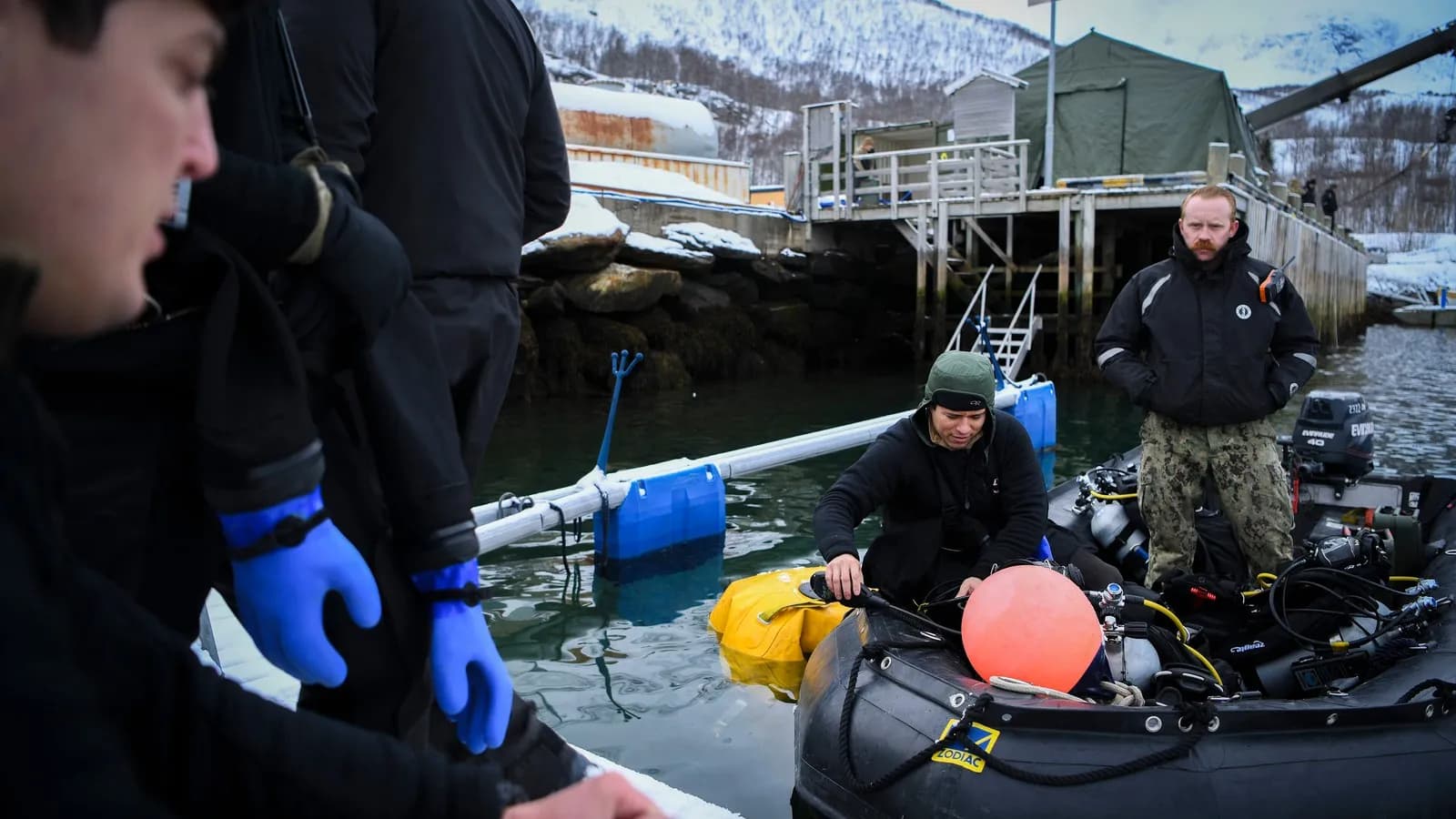 Divers in drysuits preparing on a snowy jetty in northern Norway, in a US Army photograph from March 2020