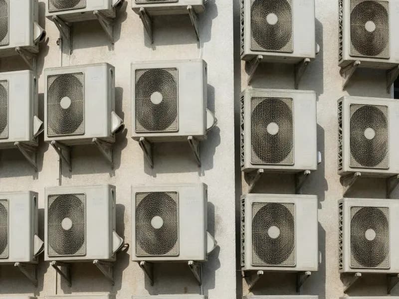 Air conditioning condenser units mounted on the side of an apartment building