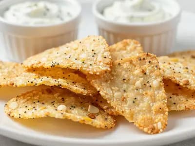 An AI-generated illustration of crispy golden cottage cheese chips topped with everything bagel seasoning on a small plate