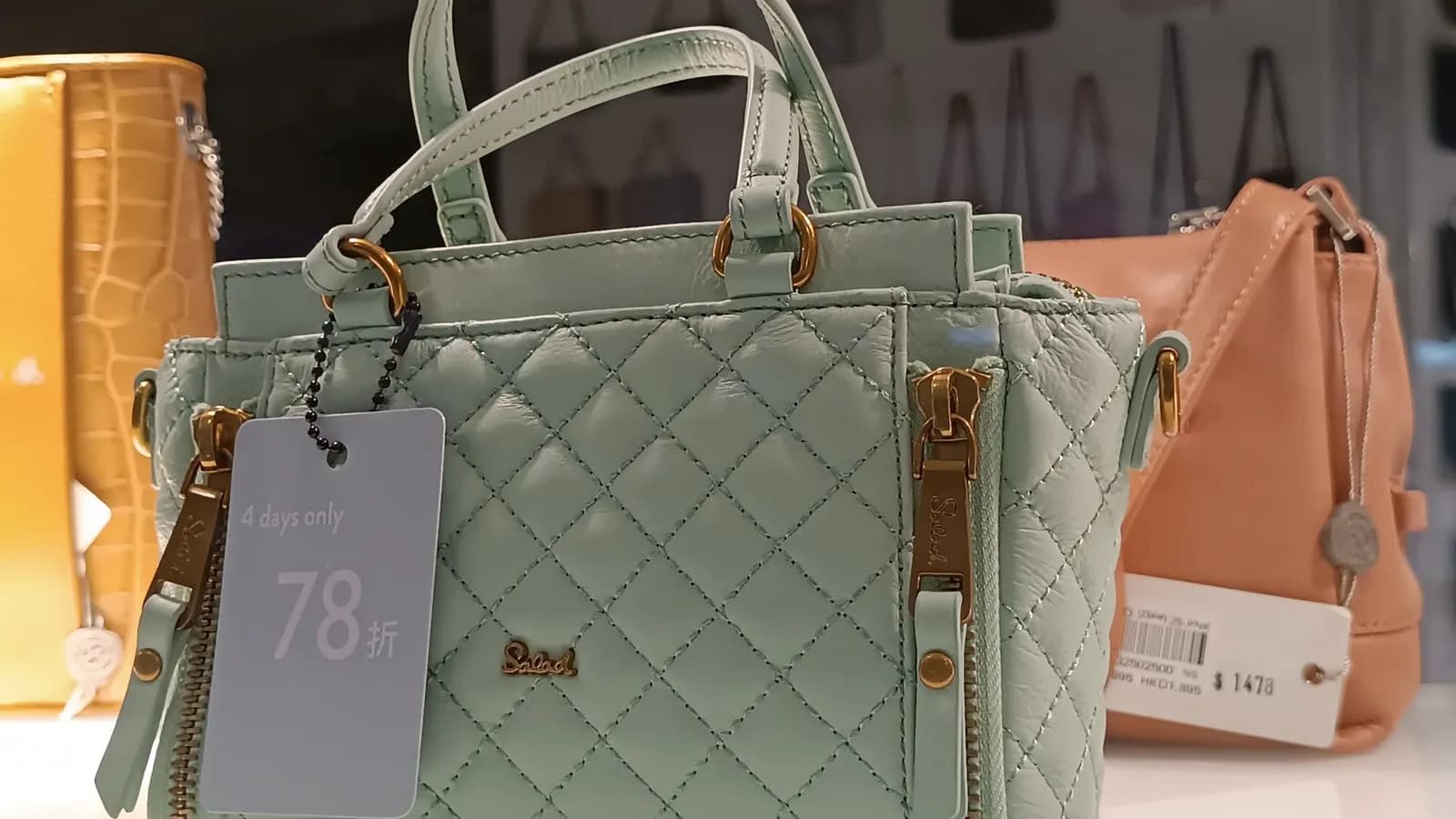 Handbags in a shop window carrying discount tags and price tickets