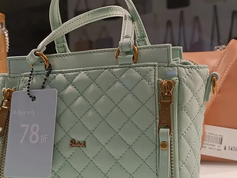 Handbags in a shop window carrying discount tags and price tickets