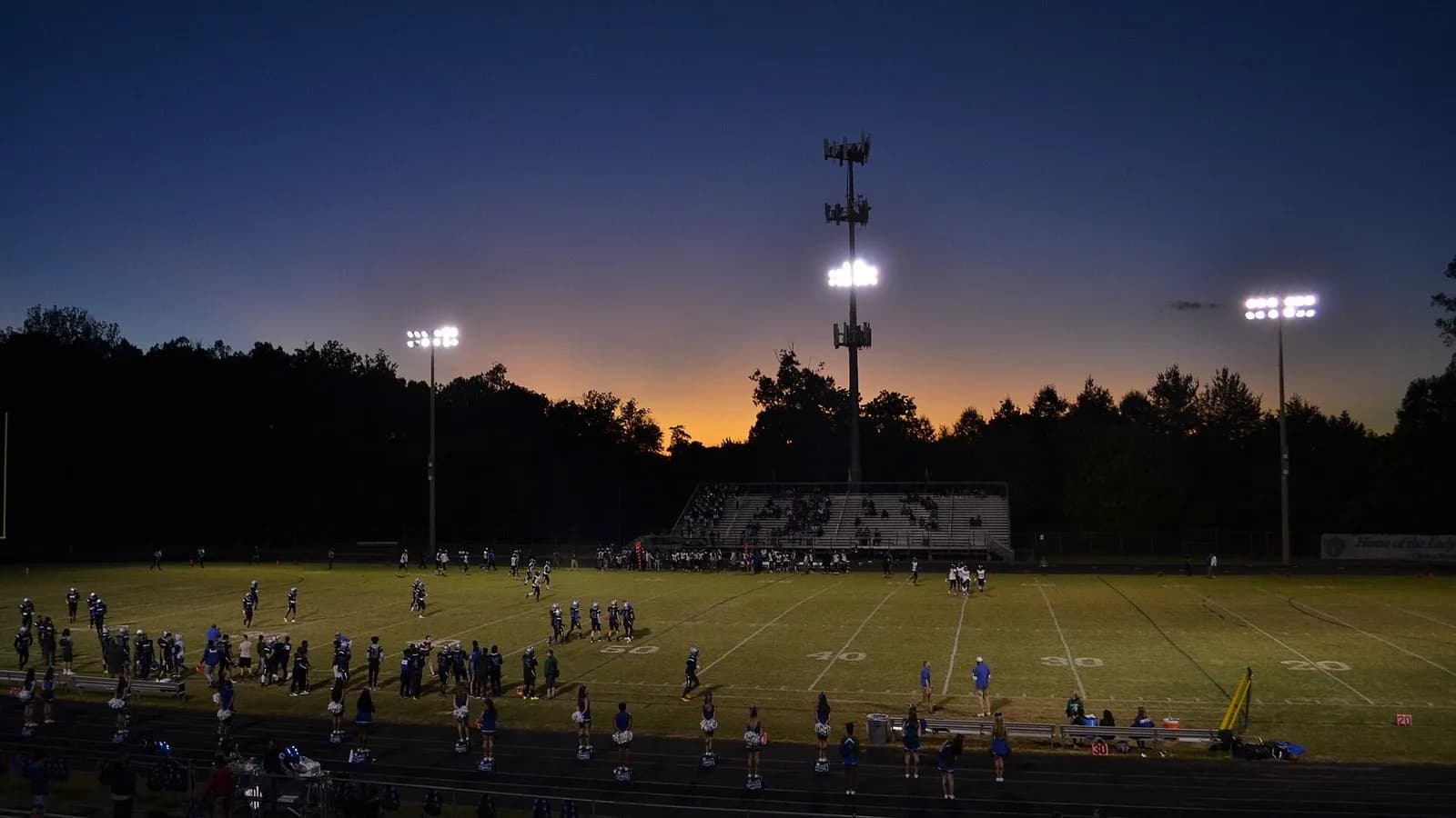 A high school football game under floodlights at sunset in Woodbridge, Virginia, seen from a distance with the players small on the field, photographed on 4 October 2019, a file photograph illustrative of American football and not of any NFL player in the study