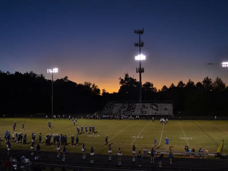 A high school football game under floodlights at sunset in Woodbridge, Virginia, seen from a distance with the players small on the field, photographed on 4 October 2019, a file photograph illustrative of American football and not of any NFL player in the study