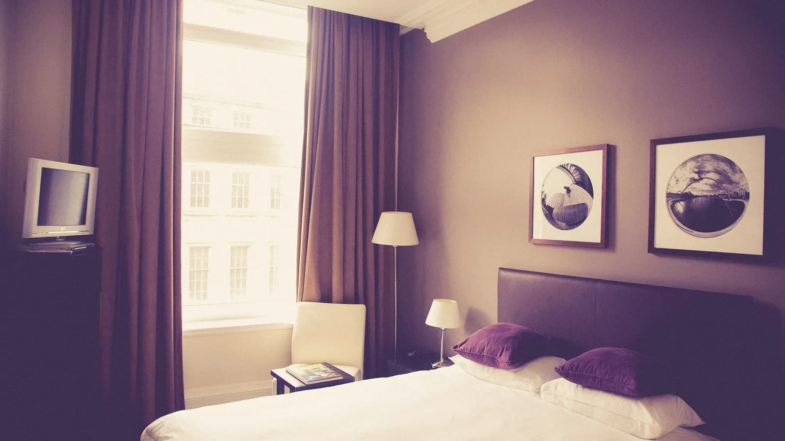 A hotel bedroom with lined curtains drawn back from tall windows, photographed in 2015