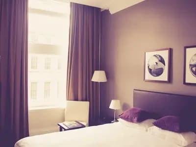 A hotel bedroom with lined curtains drawn back from tall windows, photographed in 2015