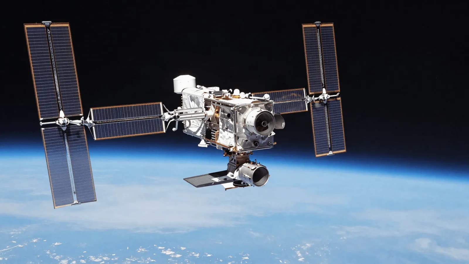 A satellite with extended solar arrays in orbit above the curve of the Earth