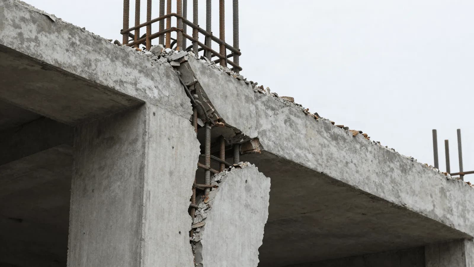 A cracked concrete column exposed after an earthquake, reinforcement bars visible