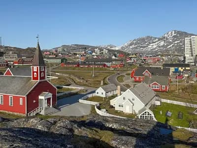 A view of Nuuk, the capital of Greenland, with its red wooden cathedral and the hills behind, photographed in June 2025, a file photograph of the town and not of any exploration site