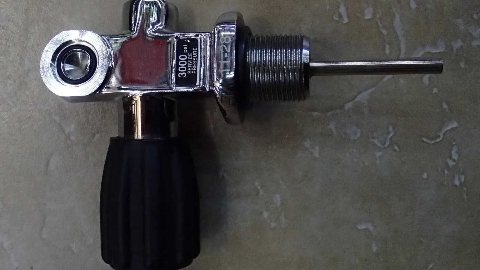 A scuba cylinder valve in close up, showing the threaded outlet, the handwheel and the pressure rating stamped into the body