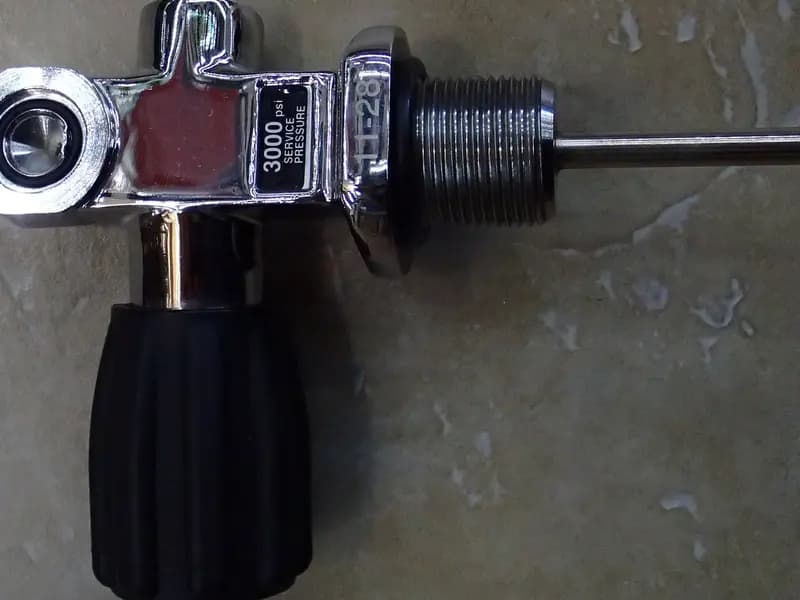 A scuba cylinder valve in close up, showing the threaded outlet, the handwheel and the pressure rating stamped into the body