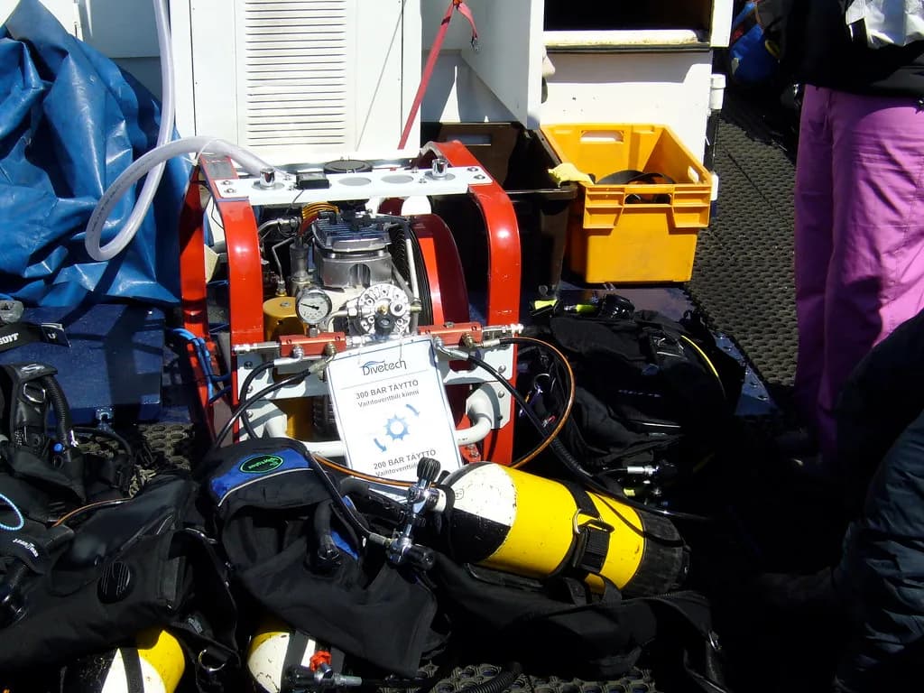 A laminated diving emergency contact card resting beside a first aid kit on a dive boat