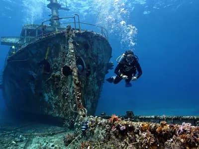 A diver approaching a sunken shipwreck in blue water