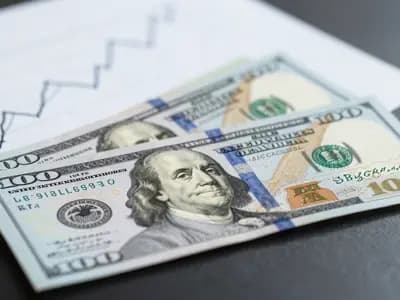 US dollar banknotes on a desk beside a printed chart