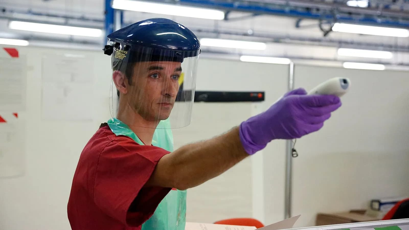 A health worker in a face shield and purple gloves pointing a temperature scanner, from a photograph captioned as taking temperatures to check for Ebola, taken in November 2014, a file photograph illustrative of Ebola screening and not of Congo or Kenya in 2026