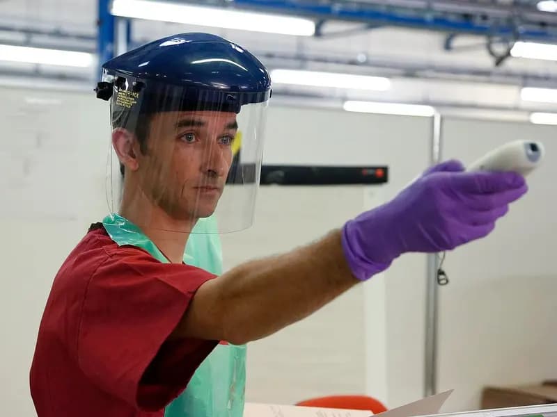 A health worker in a face shield and purple gloves pointing a temperature scanner, from a photograph captioned as taking temperatures to check for Ebola, taken in November 2014, a file photograph illustrative of Ebola screening and not of Congo or Kenya in 2026