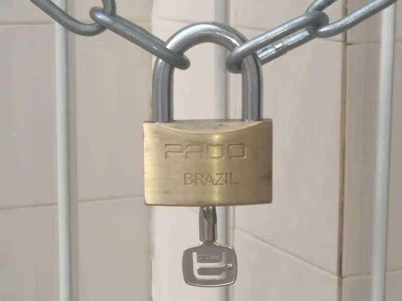 A brass padlock hanging on a steel chain against a tiled wall with its key below, photographed on 9 February 2023, a file photograph illustrative of security and not of eMudhra or its certificates
