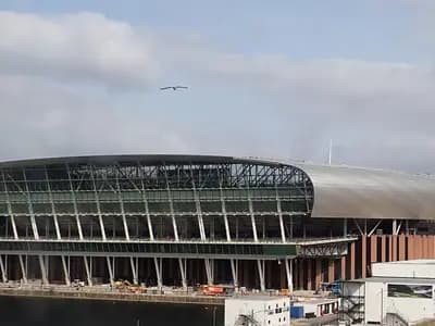 The glass-and-steel waterside facade of Everton's new stadium at Bramley-Moore Dock in Liverpool, still under construction beside the Mersey, photographed on 18 August 2024, a file photograph of the ground now called Hill Dickinson Stadium and not of Thursday night's match