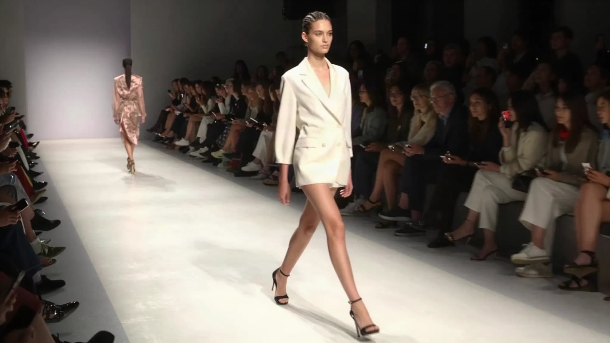 A model walking a runway under bright lights