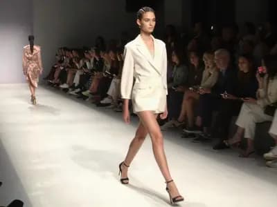 A model walking a runway under bright lights