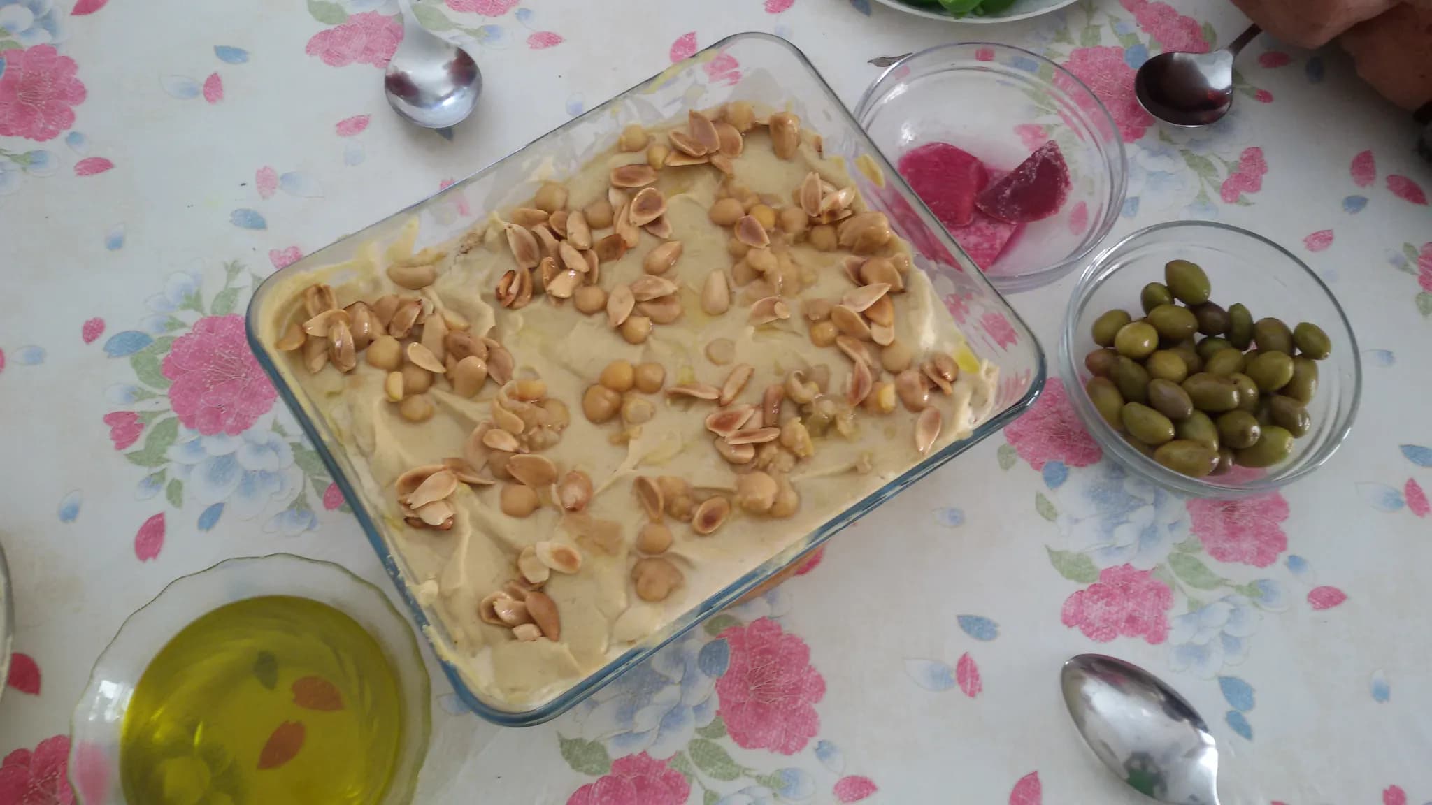 A wide dish of chickpeas and crisp pita under garlic yoghurt, topped with toasted pine nuts