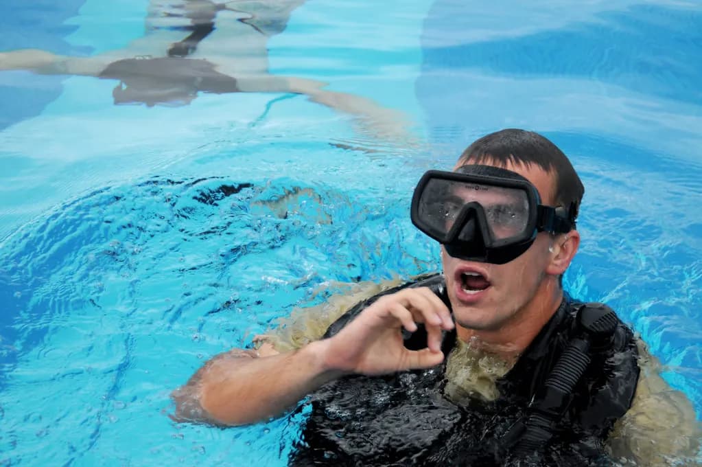 A freediver wearing a monofin descends along a guide line into deep open water