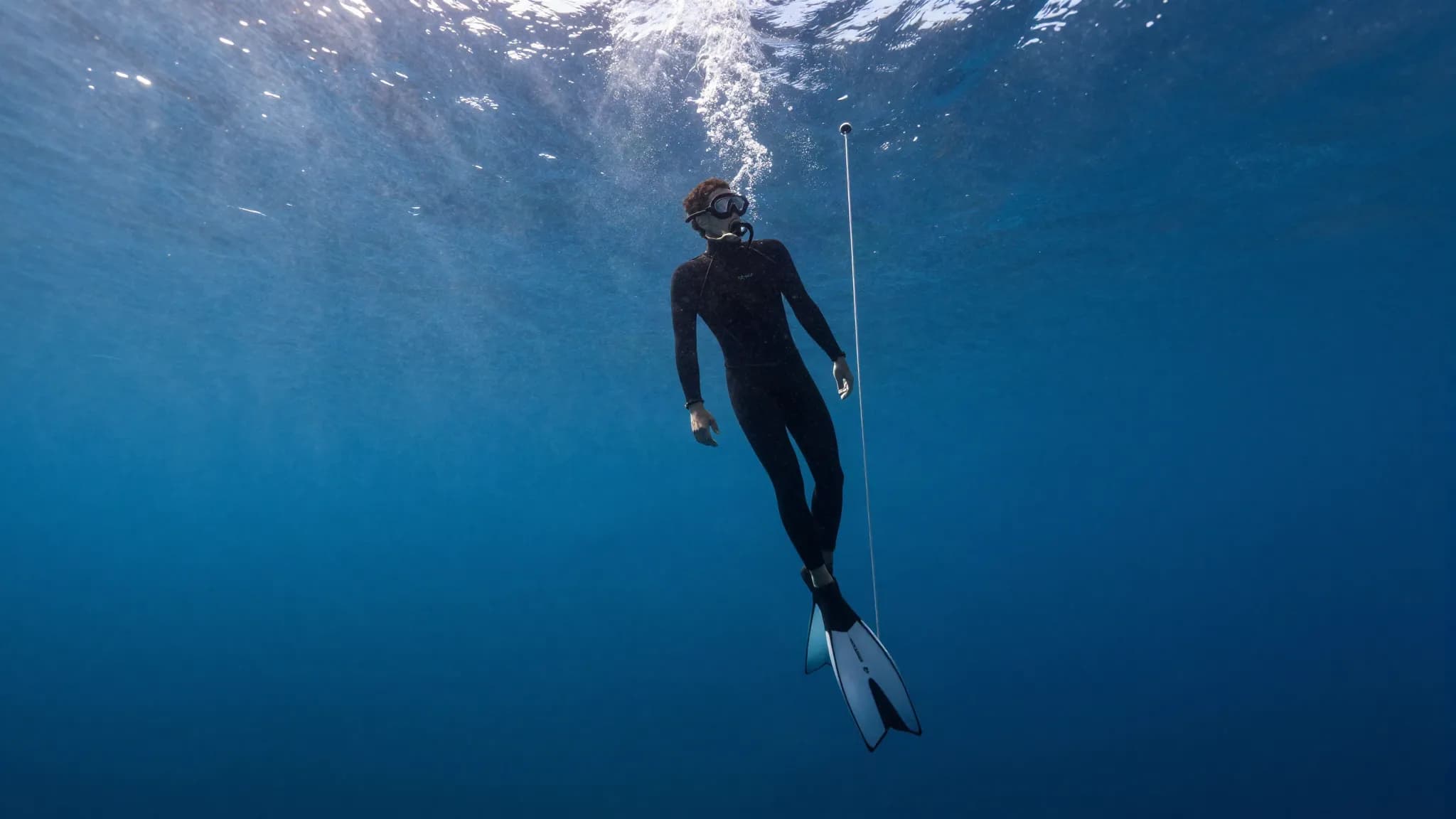 A freediver equalising while descending a guide rope